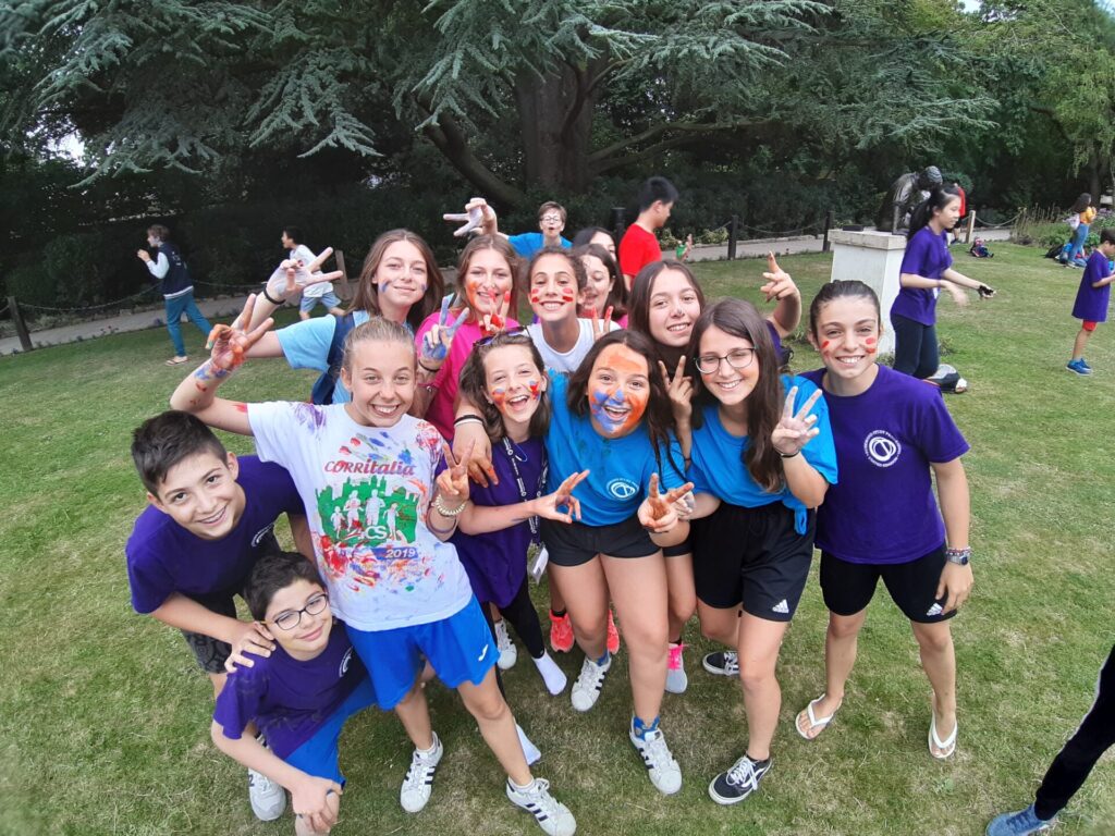 Smiling group of teenagers with painted faces posing together outdoors during a summer camp activity