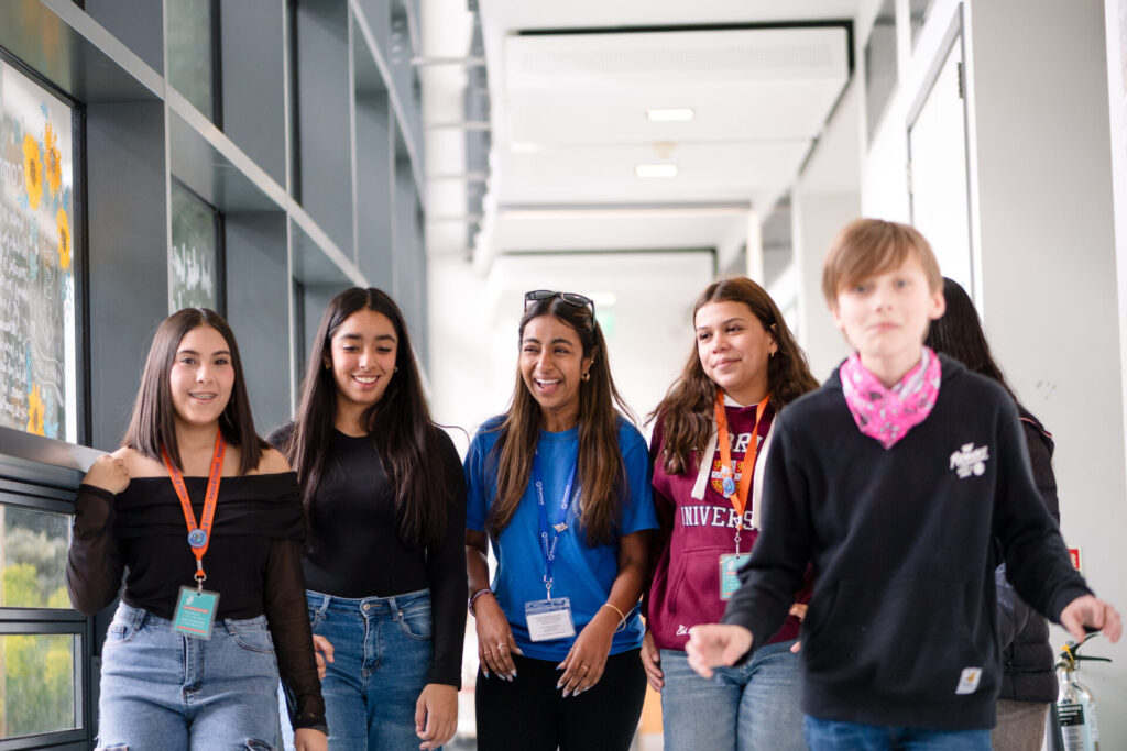 A diverse group of smiling students walking together inside a modern school hallway.