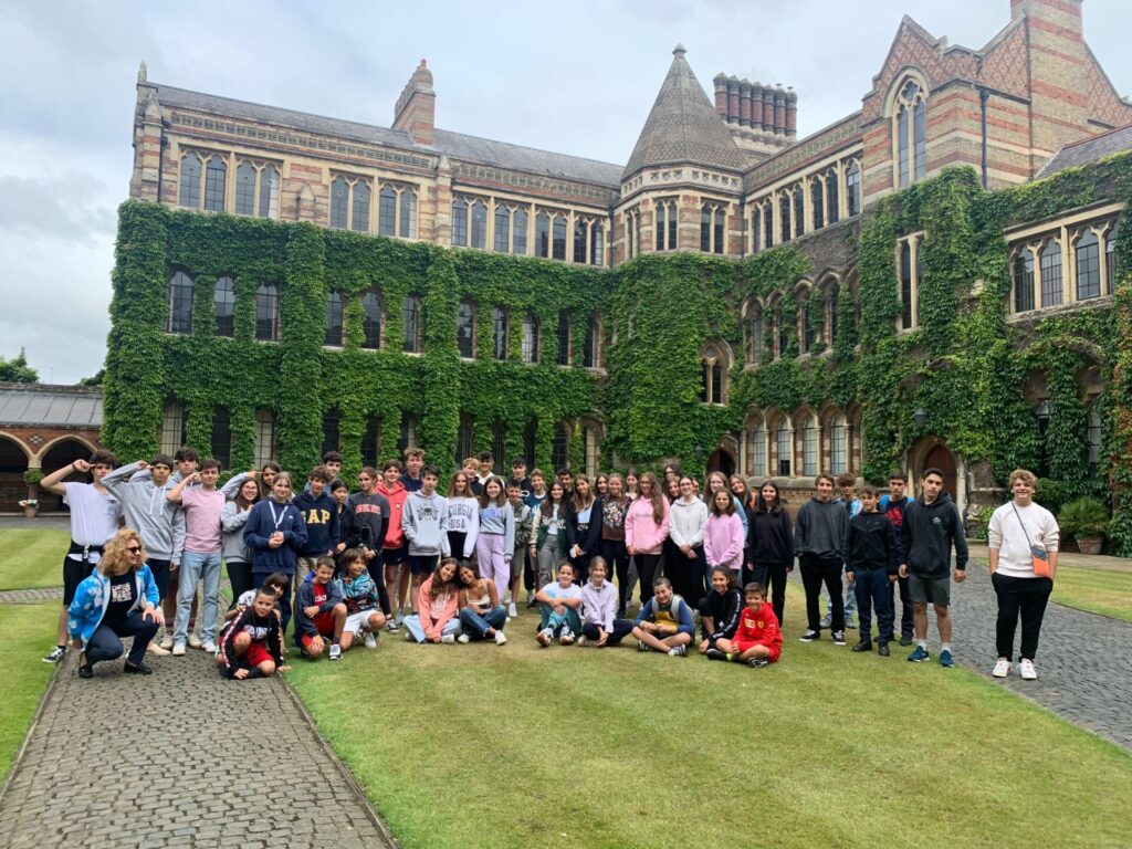 Group of students posing on the lawn of a historic ivy-covered building during a study programme or school trip